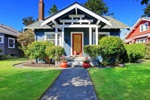 blue home with white beams and a red door. beautiful front landscaping, giving the home nice curb apeal.